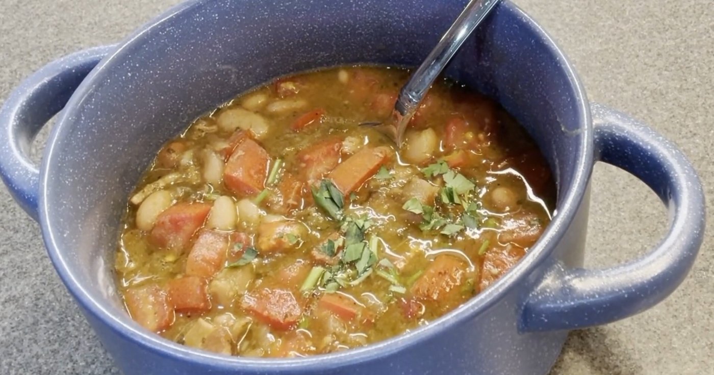 Pot of cowboy charro beans with sausage, tomato and cilantro