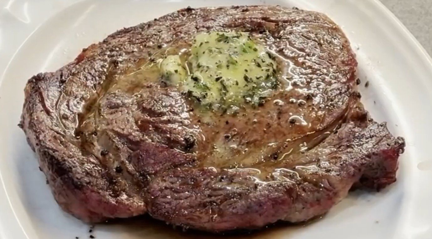 Seared ribeye steak topped with a melting round of cowboy butter