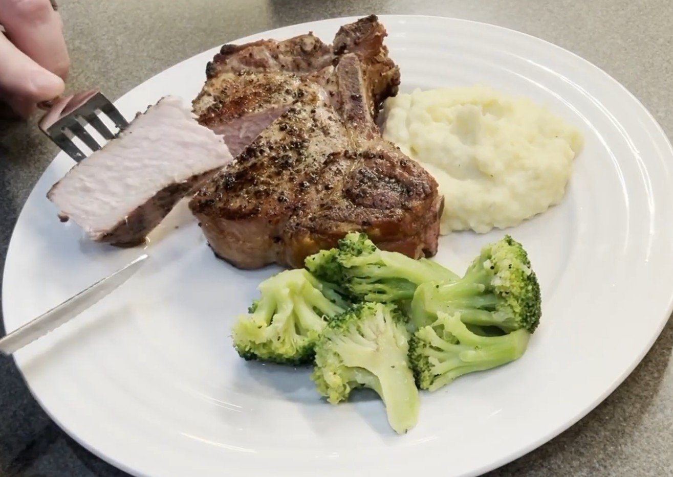 Garlic mashed potatoes served with a thick cut pork chop and broccoli