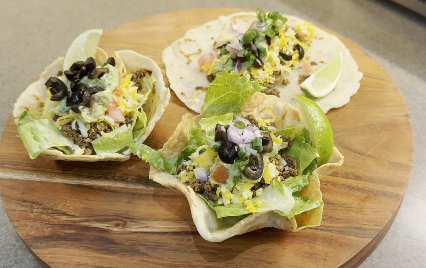 Crispy homemade tortilla taco bowls loaded with beef, guacamole, olives and lime