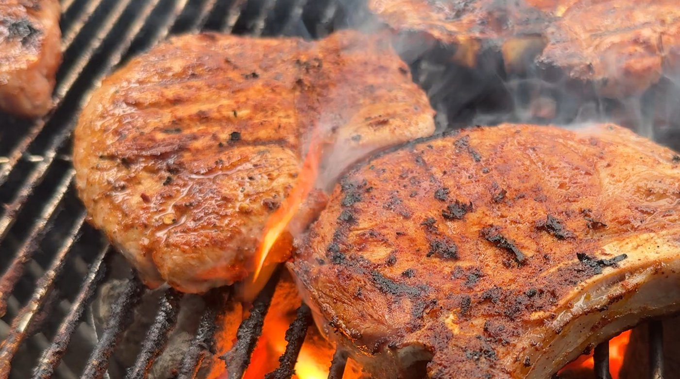 Jalapeño marinated pork chops with dark char marks, grilling over open flame