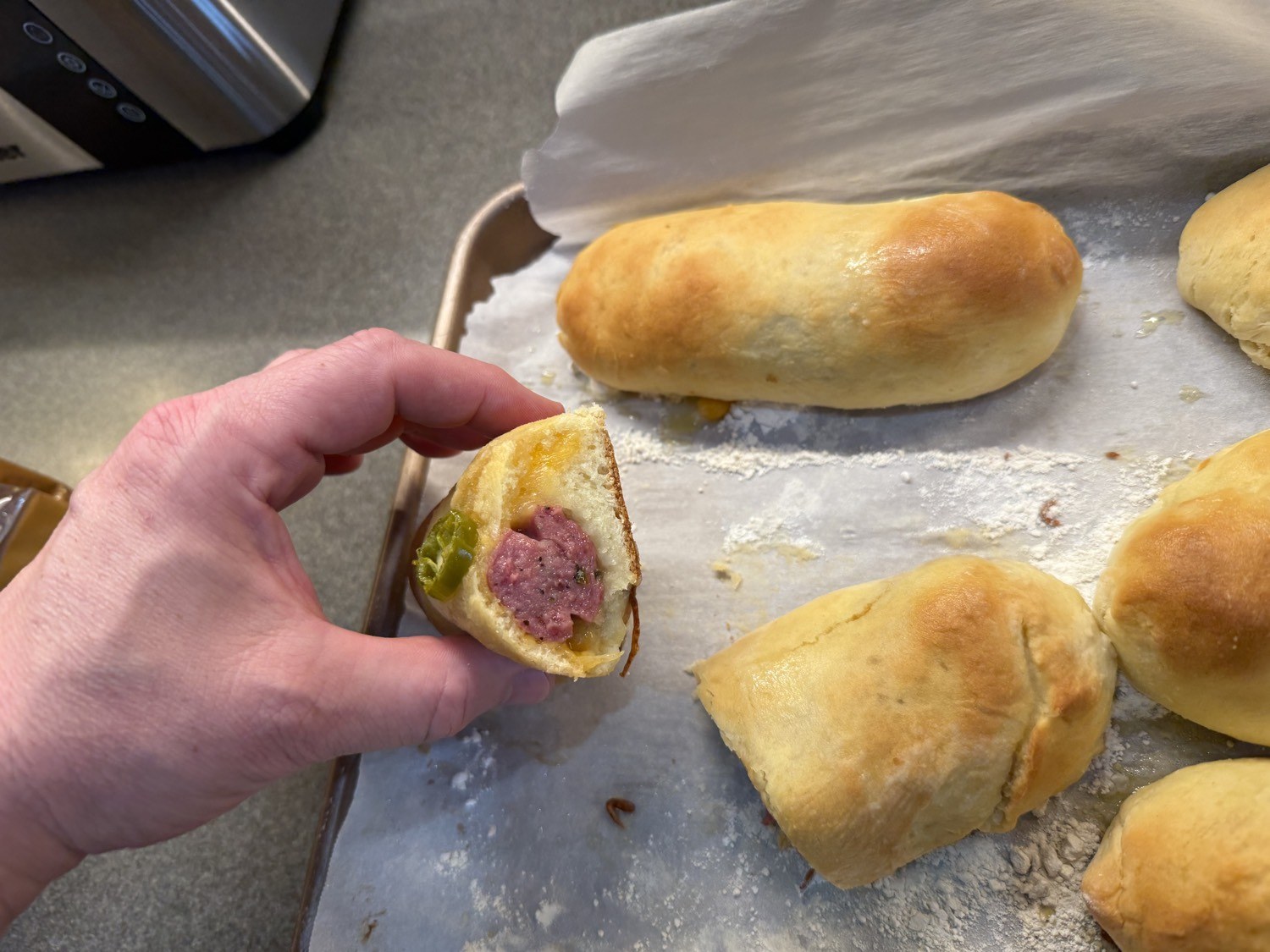 Holding a sausage kolache so you can see the filling