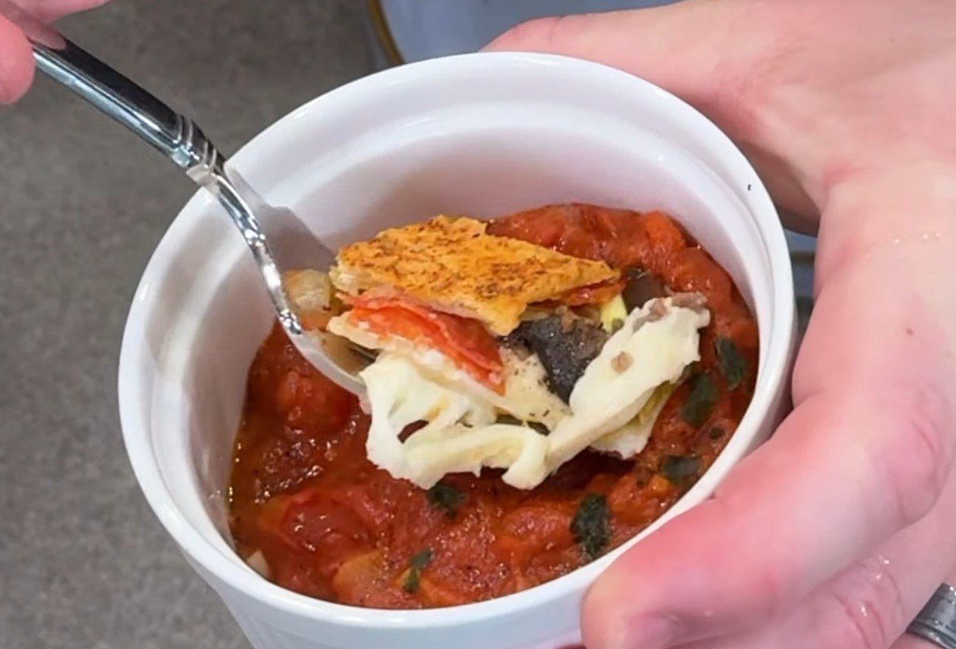 A ramekin of homemade marinara with a bite of stromboli