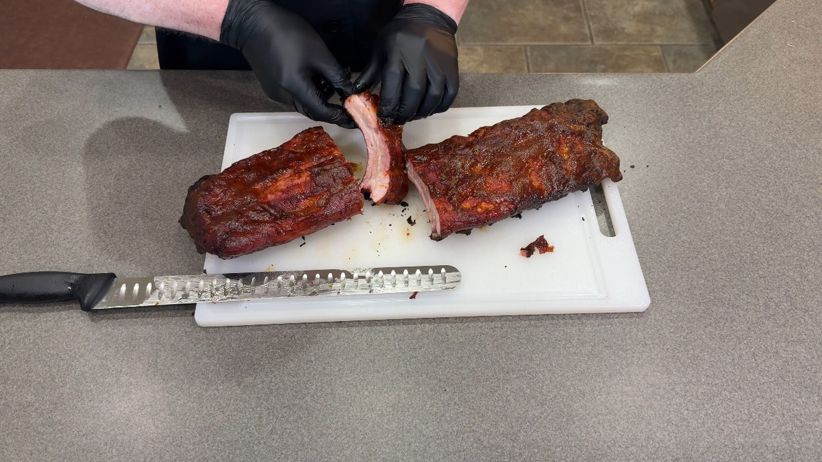 Peach Heat BBQ ribs being pulled apart on a cutting board