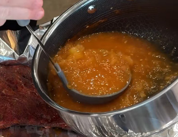 Pineapple habanero glaze in a saucepan beside smoked ribs