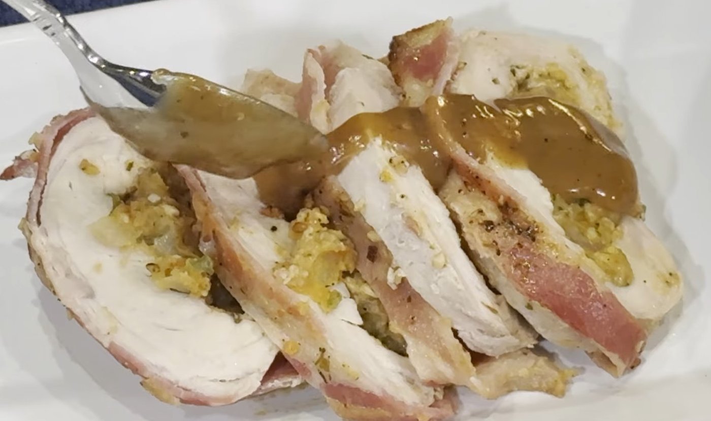 Sliced bacon wrapped stuffed pork loin with brown gravy spooned over the top